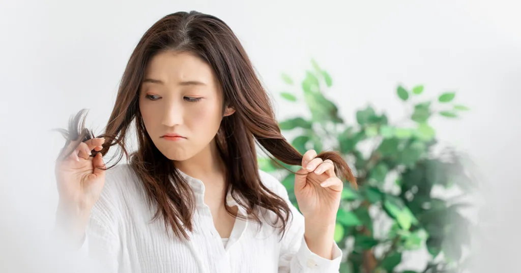 「毛先のパサつきや枝毛を気にする女性|ヘアケア商品を探すきっかけとなるシーンを表現」