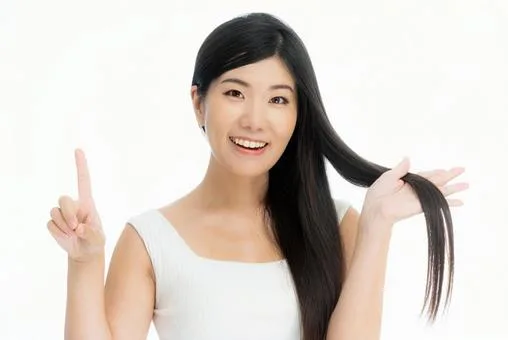 「ツヤのあるストレートヘアを見せながら笑顔で指を立てて説明する女性|ヘアケア効果やおすすめ商品を紹介するシーンのイメージ」