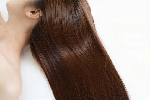 「髪に潤いを与えるヘアケアアイテムを使う女性｜自宅でサロン級の仕上がりに」