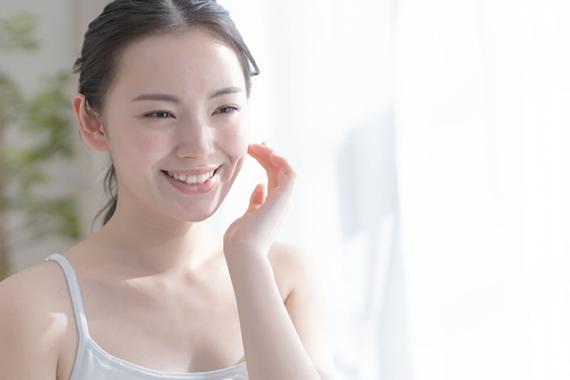 「明るい笑顔で大きく笑う若い女性のポートレート。白いシャツとナチュラルメイクが爽やかさと清潔感を演出し、幸福感や信頼感を伝えるイメージ」