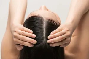 頭皮を両手でマッサージする女性の後ろ姿。シャンプー解析や頭皮ケアに関する記事用イメージ