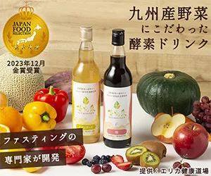 九州産野菜にこだわった酵素ドリンクを紹介する広告画像。テーブル上にカボチャ、りんご、キウイ、ぶどう、パプリカなどの野菜と果物が並び、中央に2本の酵素ドリンクボトルが配置されている。「ファスティングの専門家が開発」「2023年12月 金賞受賞」「送料無料 6,800円（税込）」と記載。提供：エリカ健康道場。